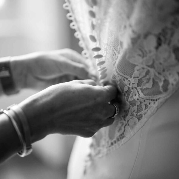 Mariée vue de dos - Une personne lui ferme sa robe