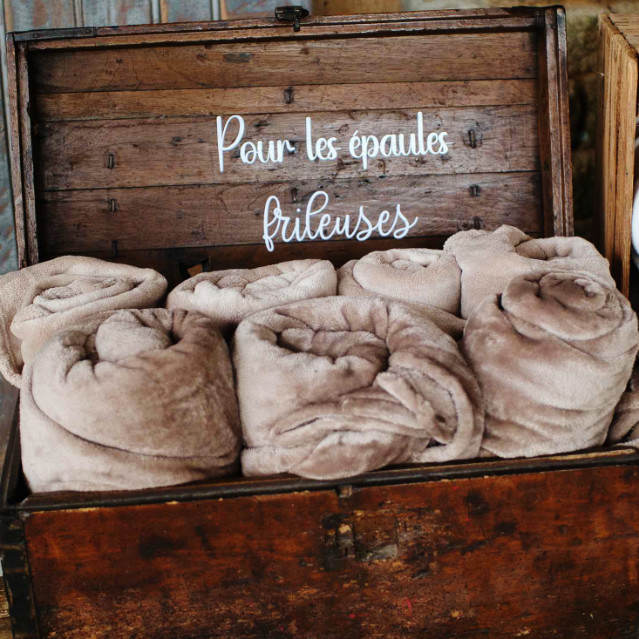 Coffre en bois avec à l'intérieur des couvertures prévues pour les épaules frileuses lors d'un mariage